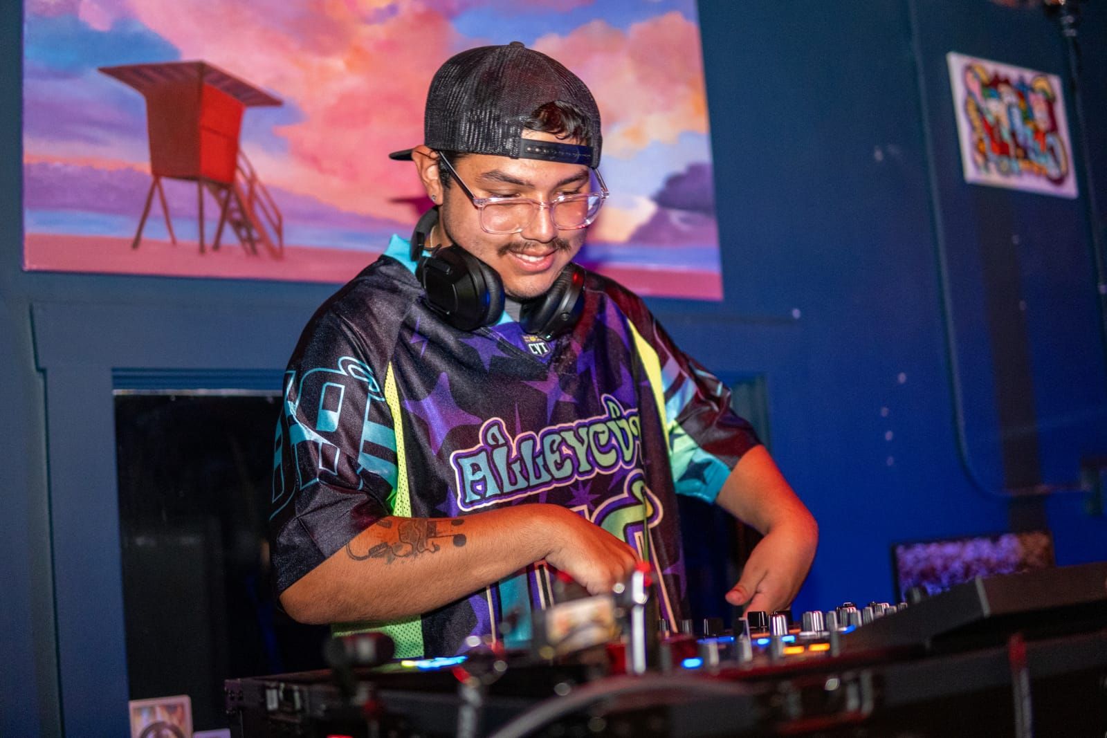 Hands on the mixer as Dill the Menace runs his set beneath the gallery's sunset mural
