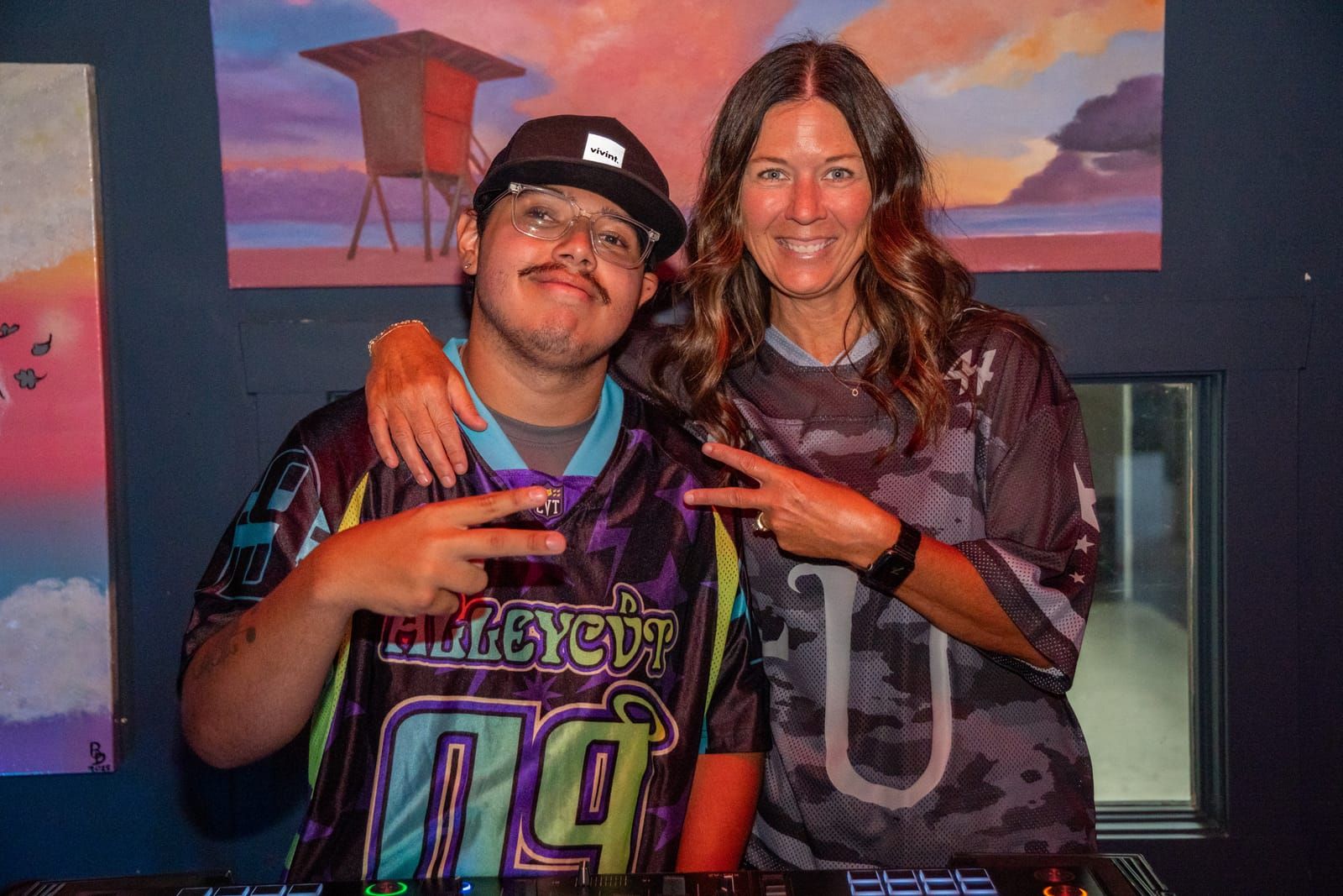 Dill the Menace and a fan throwing up peace signs beside the DJ booth