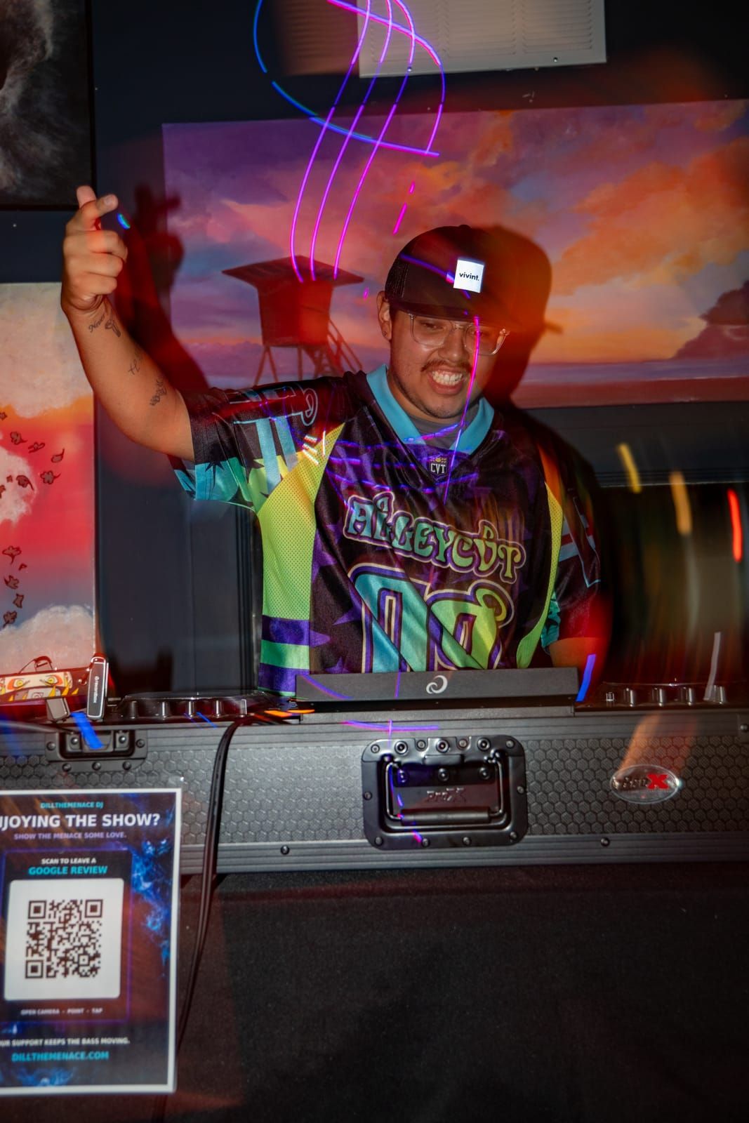 Dill the Menace hyping the room with an arm in the air behind the decks