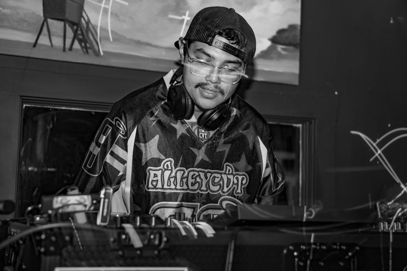 Light trails streak across a moody black and white shot of the DJ booth